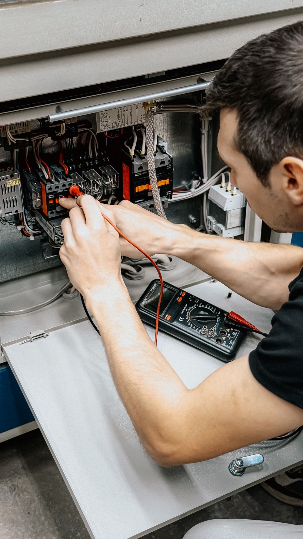 An electrician testing an electrical panel with a multimeter
