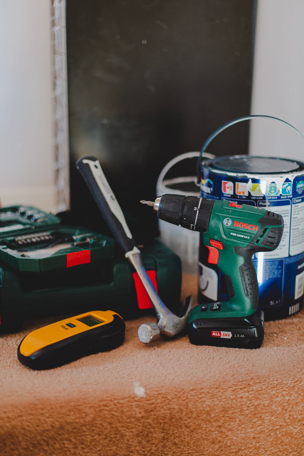 A drill, hammer and paint supplies laid out for a home project