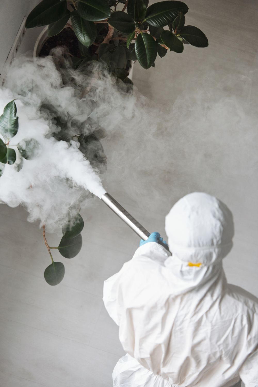 A pest control technician in protective clothing treating a room
