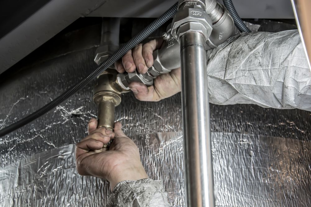 A plumber's hands fitting a steel pipe