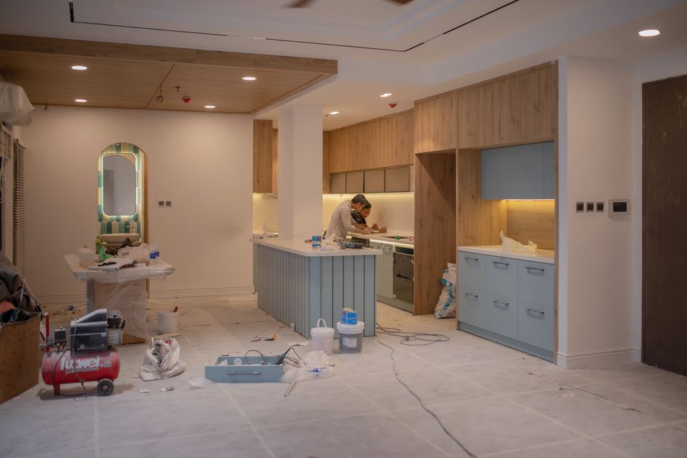 A kitchen mid-renovation with a worker, tools and materials