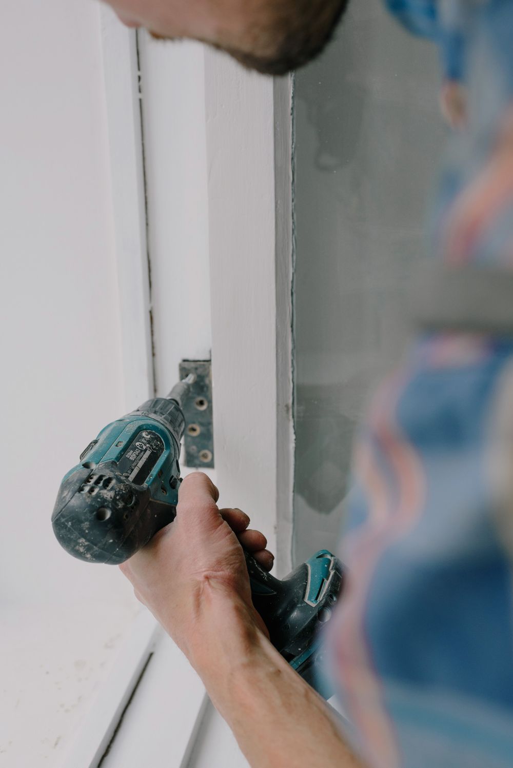 A fitter installing a new window frame with a screwdriver